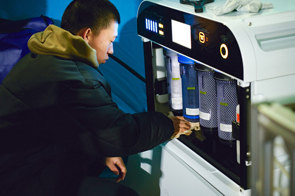 A middle school student wiping compact units inside a WOTA BOX at an evacuation center in Noto.