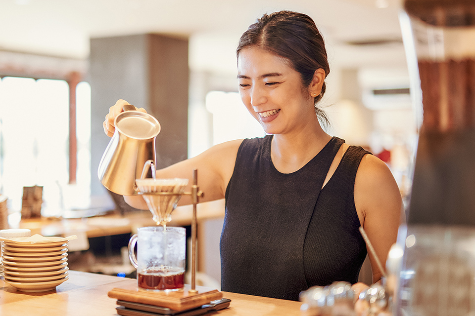 A woman pouring water into the coffee maker.