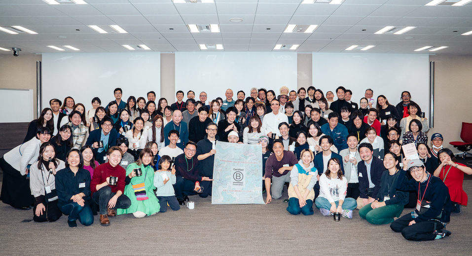 Large group of people posing in a room with a central poster