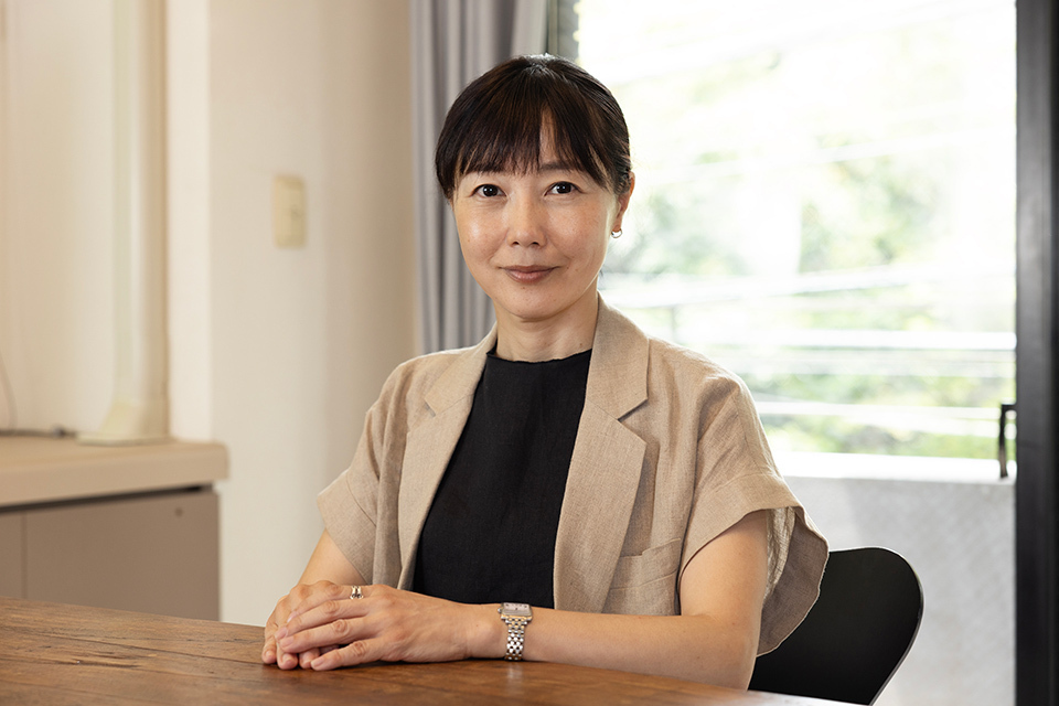 An individual sits at a table with their hands clasped together.