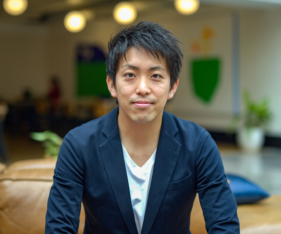 Ueda Akihiro, CEO of Terra Motors, smiling in casual business attire, seated in modern space.