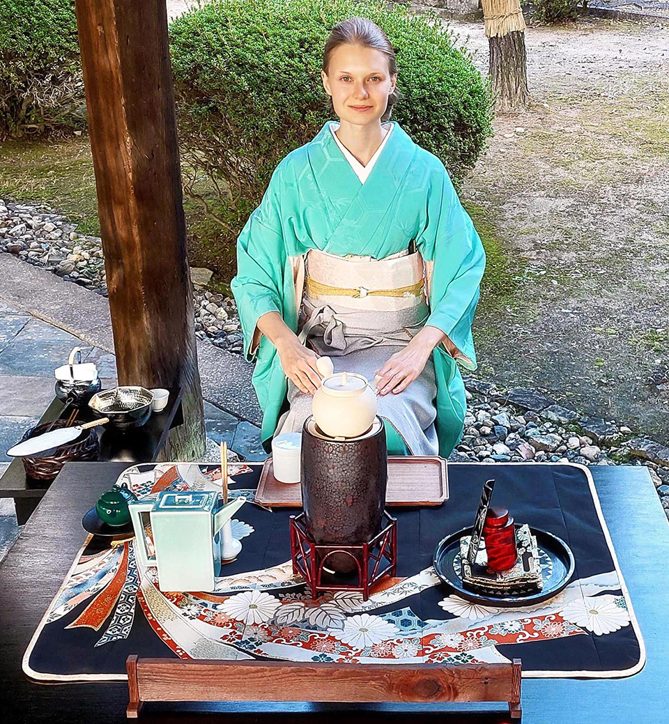 A woman wearing blue kimono serving sencha green tea at a tea ceremony