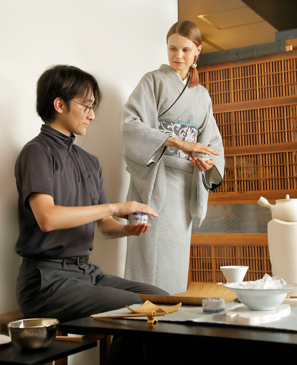 Senchado lesson: A woman in kimono teaching tea preparation to a man, Japanese sencha tea table setup in foreground