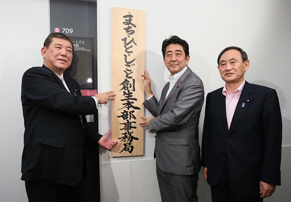 Three men in suits stand together, holding the headquarters sign in Japanese.