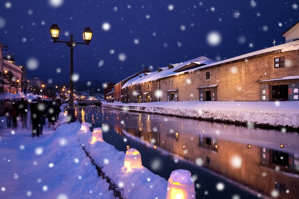 Snowflakes descend softly over the Otaru Candlelit Canal, illuminating the town with a magical winter charm.