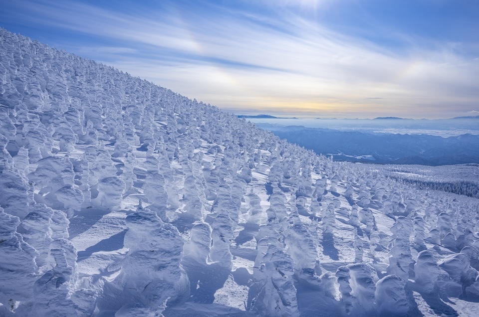 Sunlit snow-covered mountains with the distinctive snow monsters of Mt. Zao creating a stunning winter landscape.