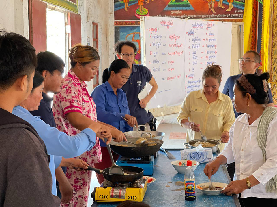 A diverse group of individuals collaborates around a table, engaged in food preparation activities.