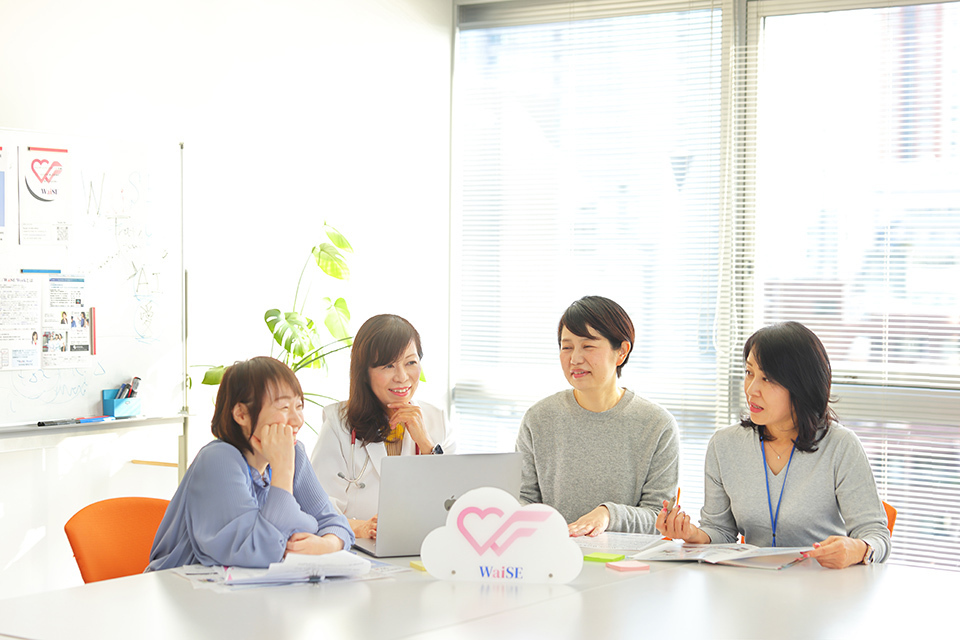 Women collaborating at a table, focused on a laptop, fostering a productive and inclusive environment.