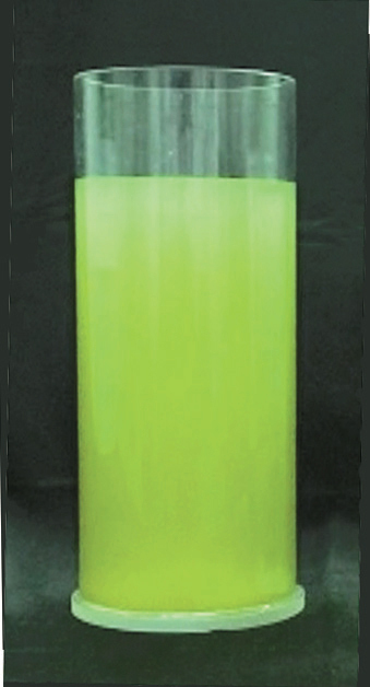 A cylindrical glass filled with green liquid that needs to be purified, with a black surface in the background.